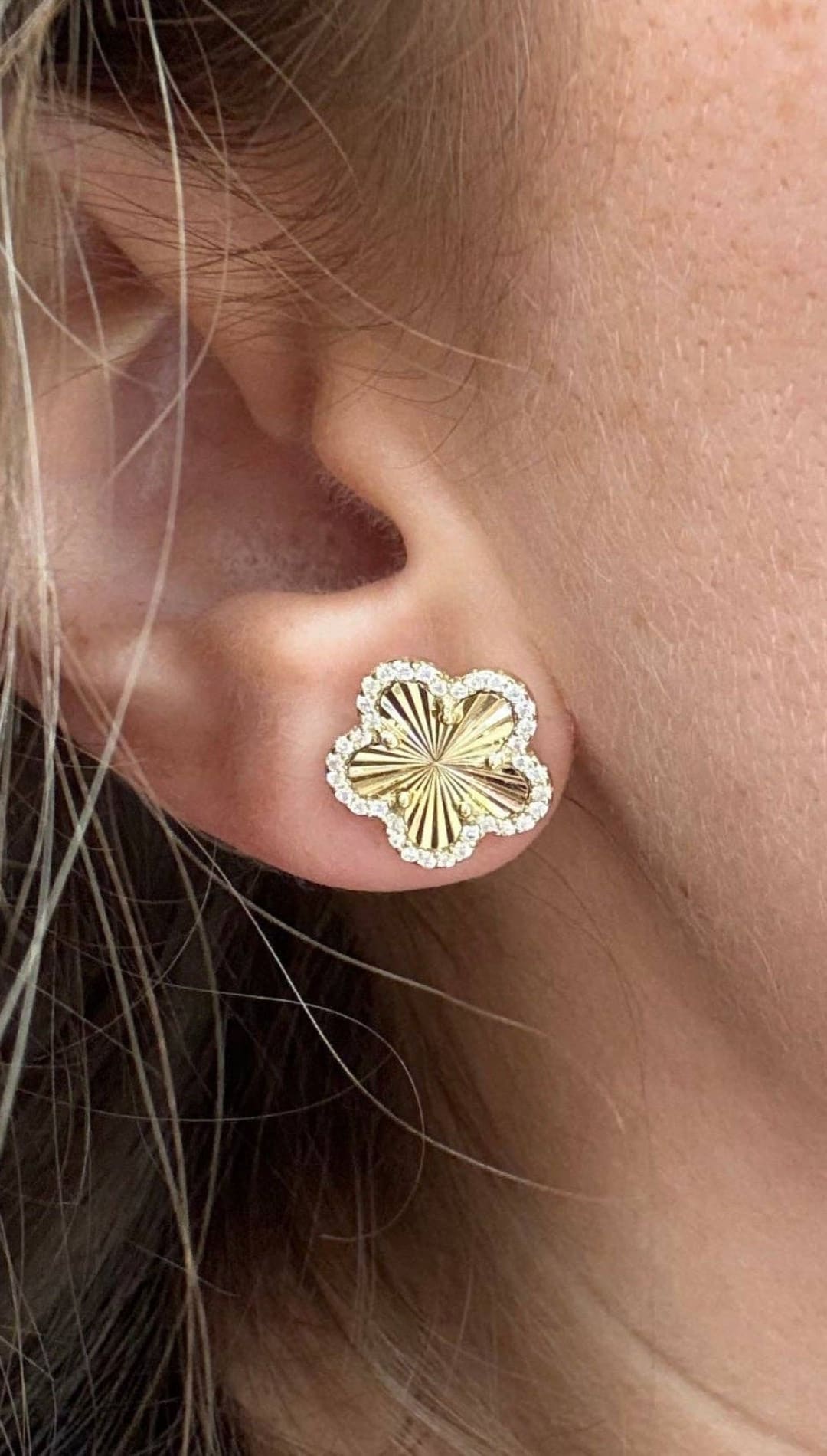 Gold flower-shaped earring with diamond trim.