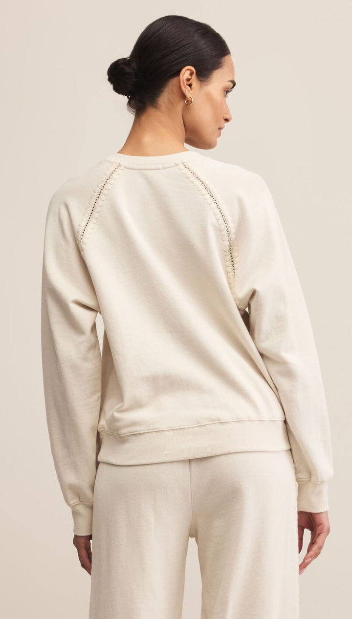 Cream-colored sweatshirt with gold chain detailing on the shoulders.