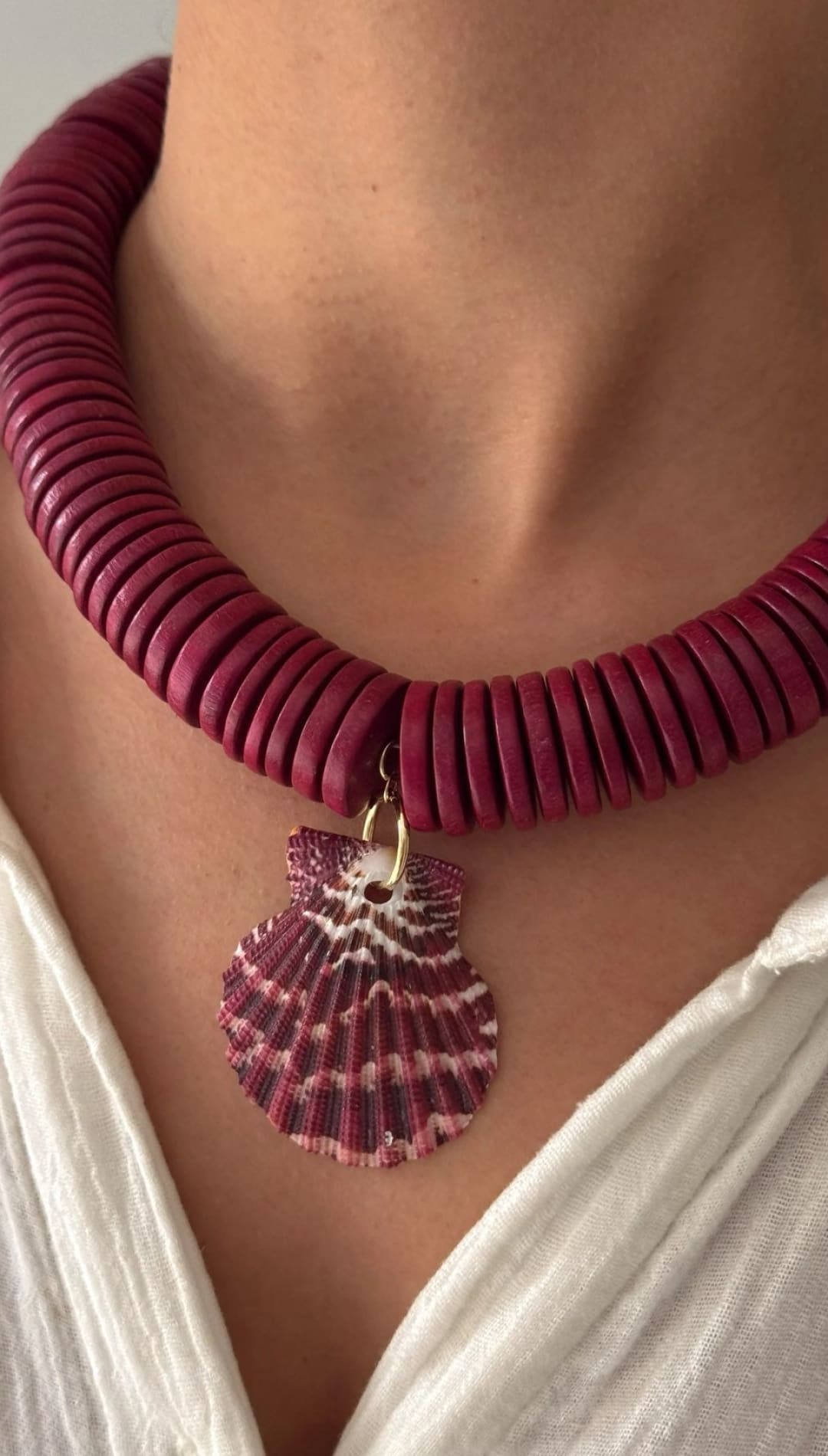 Maroon disc necklace with shell pendant.
