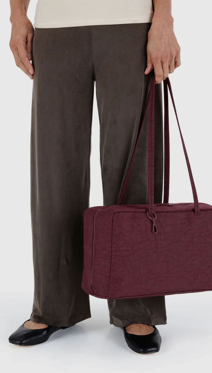 Burgundy textured tote bag with leather handles and drawstring closure.