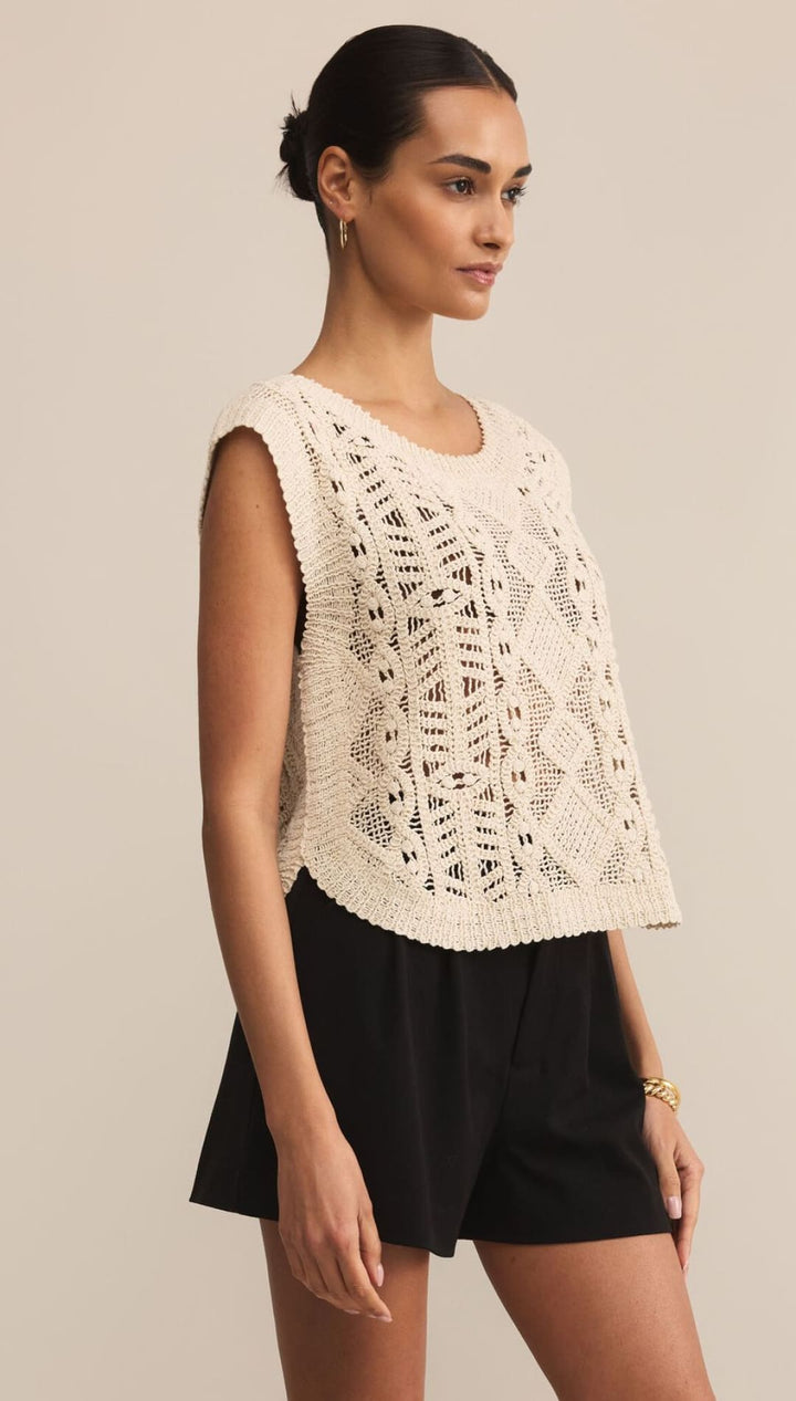 Women’s cream-colored crochet knit sleeveless top with black shorts.