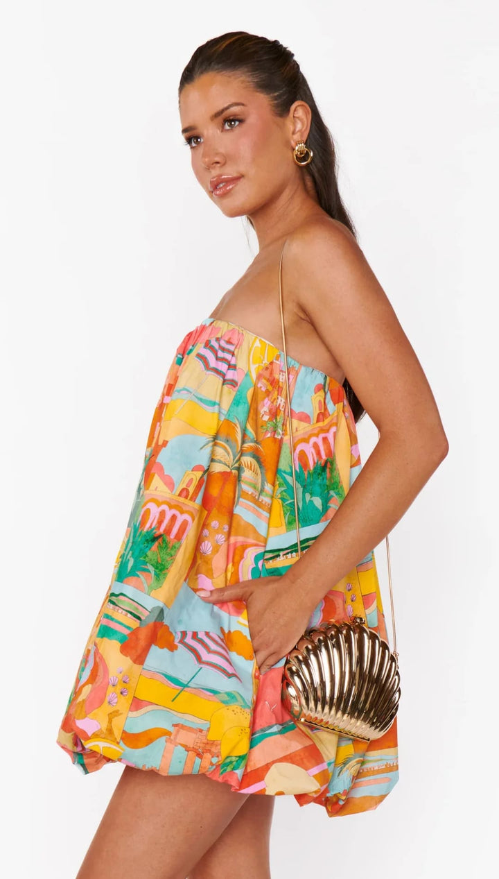 Woman in colorful strapless dress with seashell purse.