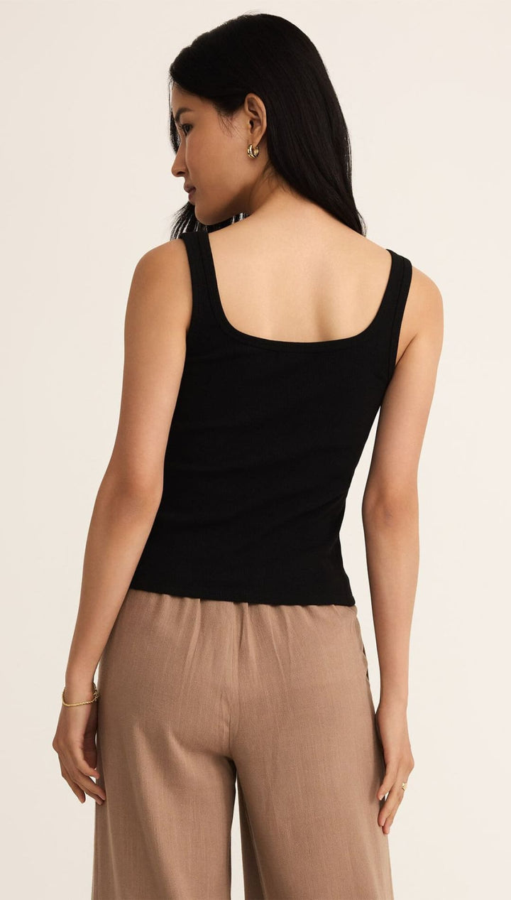Woman’s black tank top and tan pants.