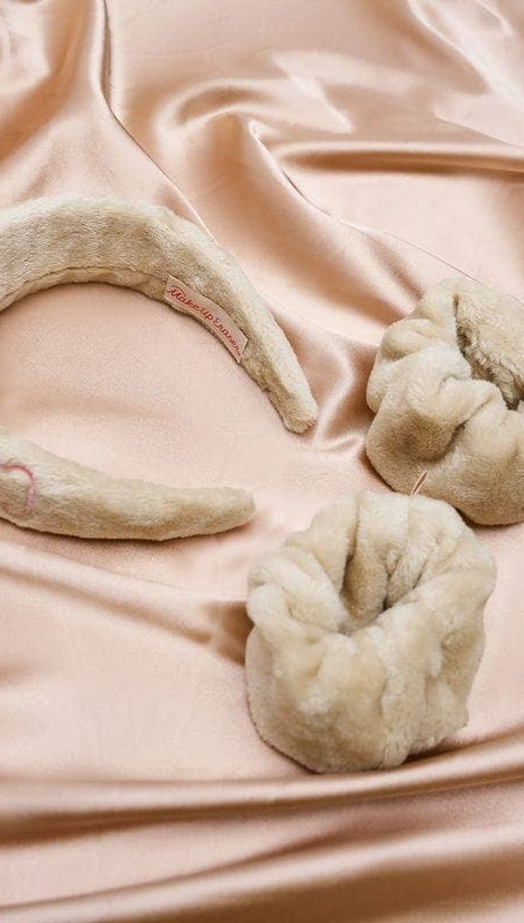 Cream-colored plush headband with a bow detail and elastic band, likely from the brand ’urban outfitters.’