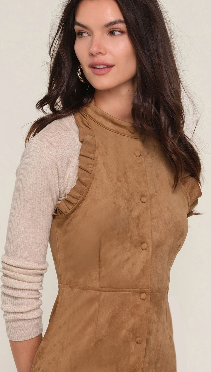 Brown corduroy sleeveless dress with ruffled neckline and button front closure.