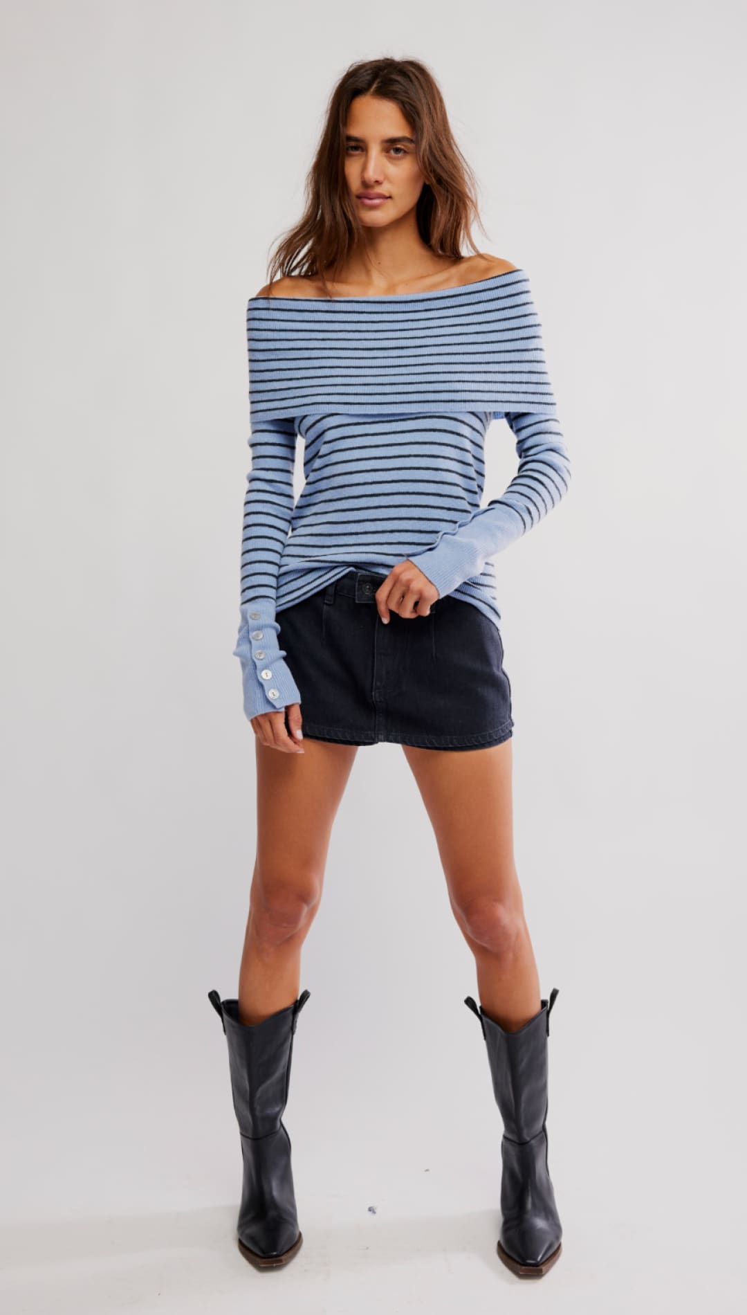 Woman in striped off-the-shoulder top, dark skirt, and black boots.