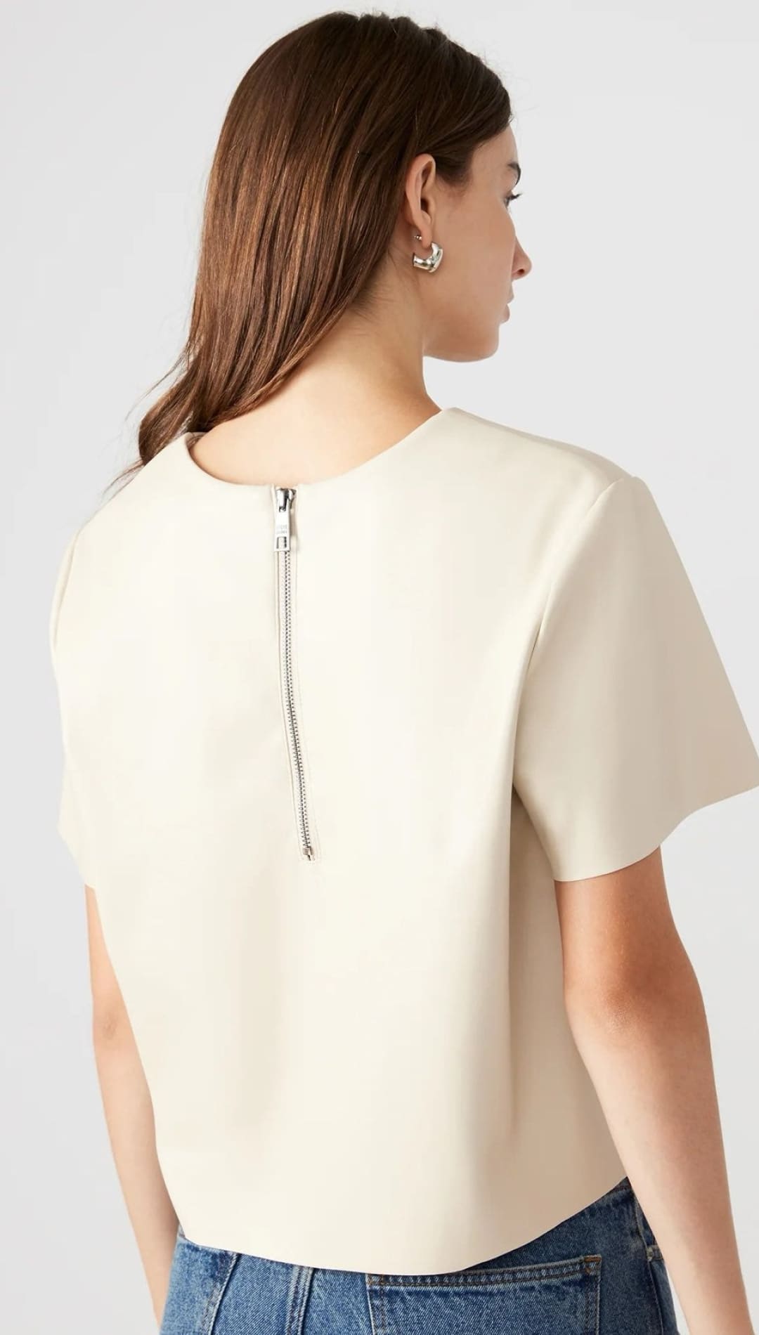 A cream-colored short-sleeved top with a visible silver zipper down the back.