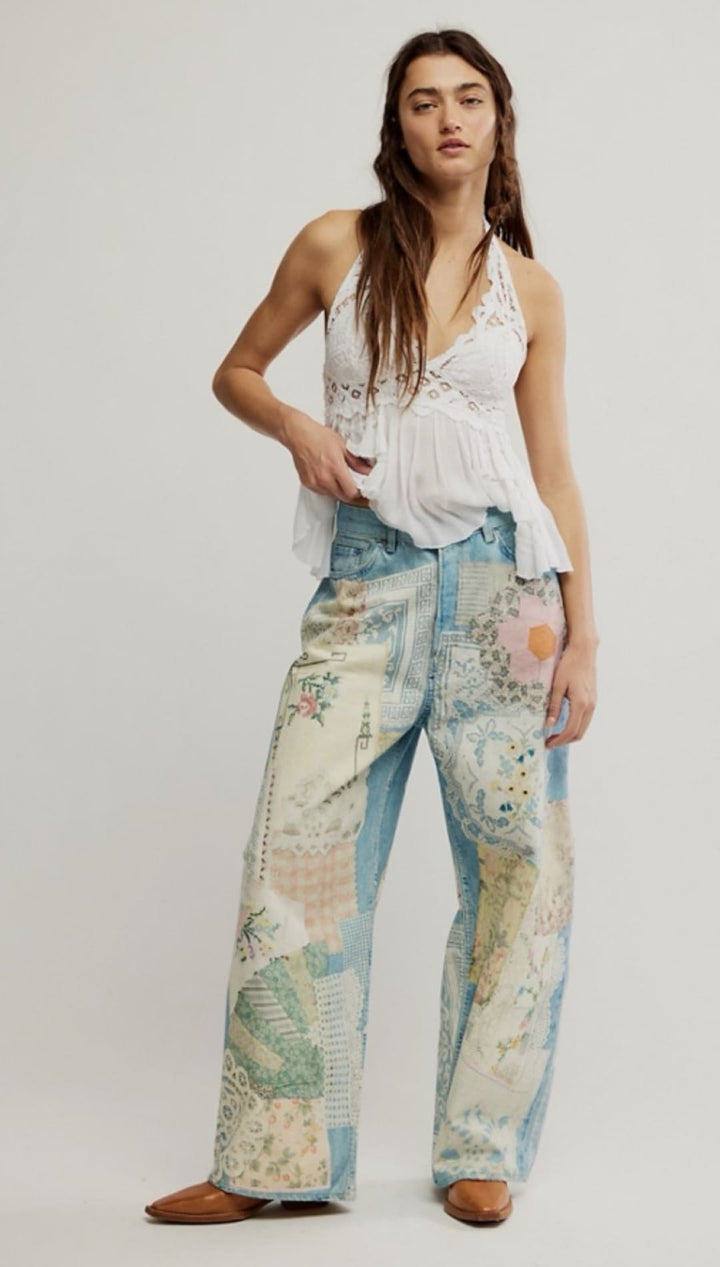 Woman wearing patchwork jeans and a white halter top.