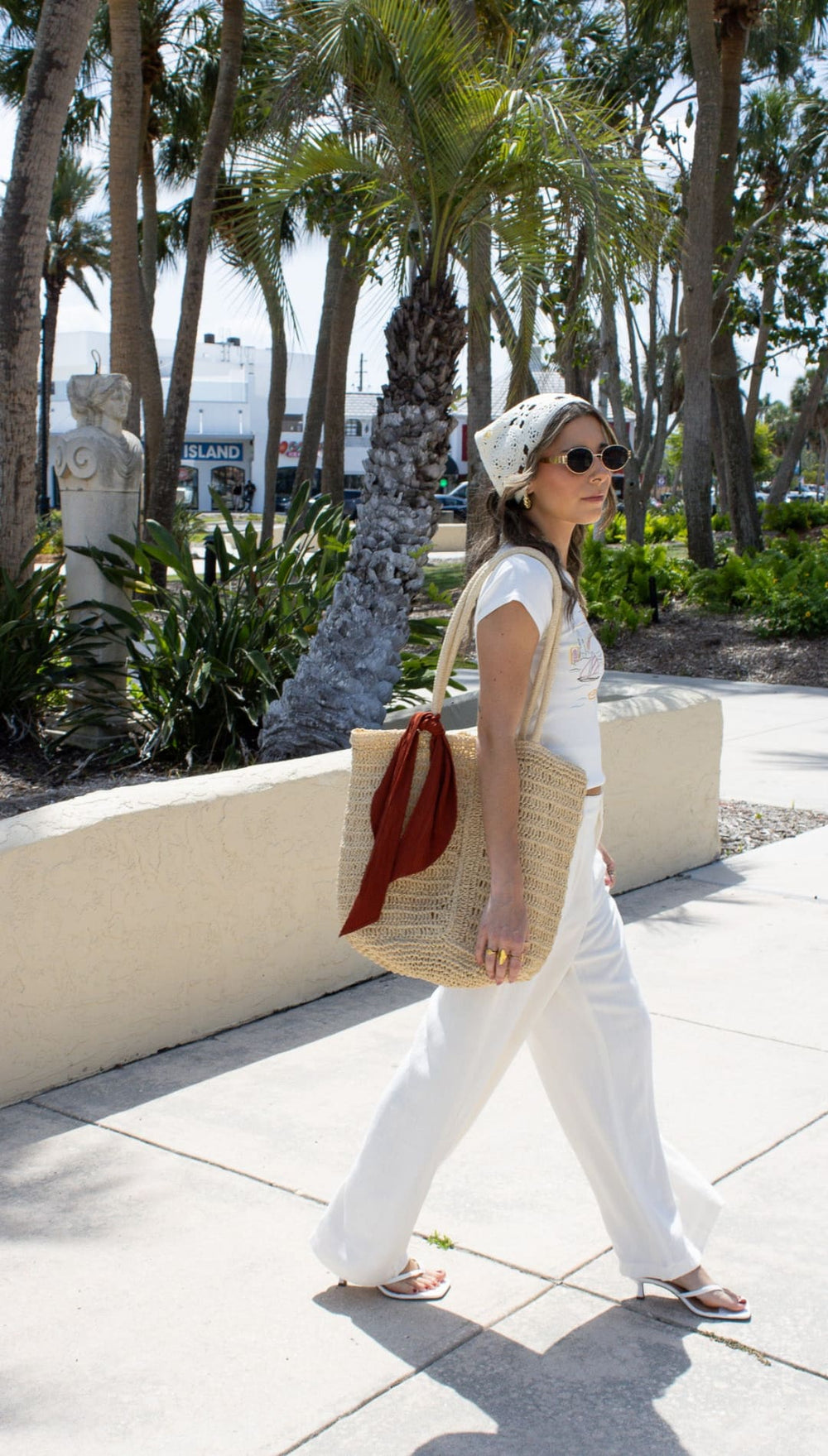 Woman in white outfit with straw tote bag.