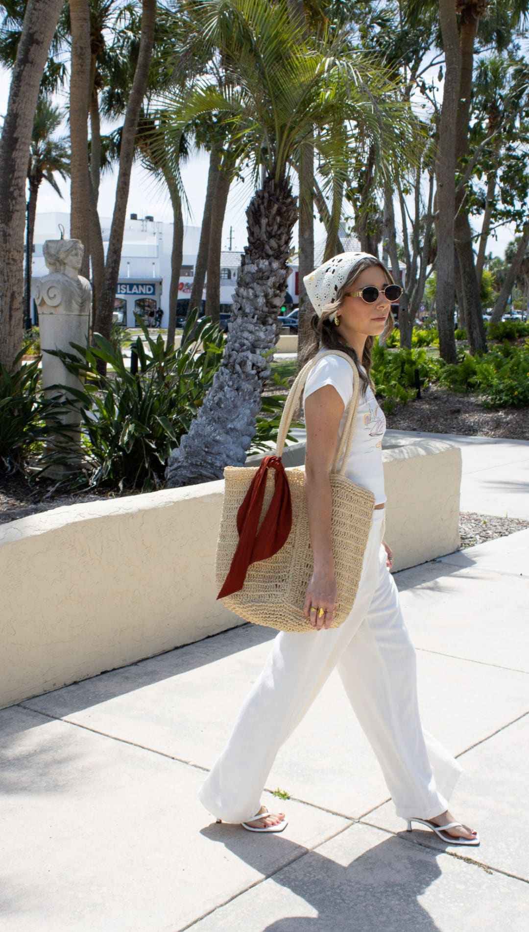 Woman in white outfit with straw tote bag.