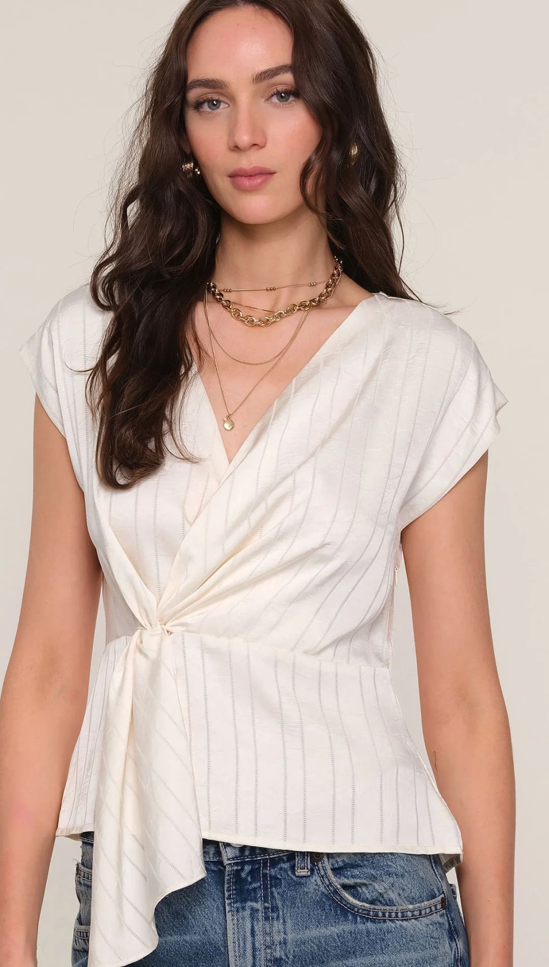 Women’s off-white pinstriped short-sleeve top with a V-neck and a front knot detail.