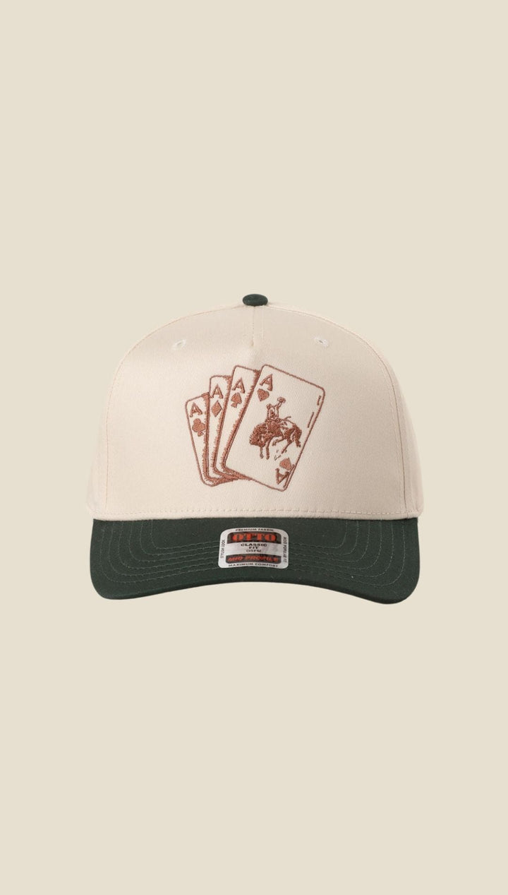 Cowboy-themed baseball cap with a cream-colored front and green brim, featuring an embroidered design of playing cards.