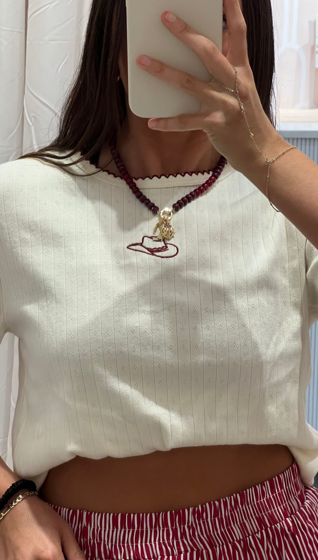 A white short-sleeved top with a scalloped neckline and sleeves, featuring a cowboy hat embroidery on the front.