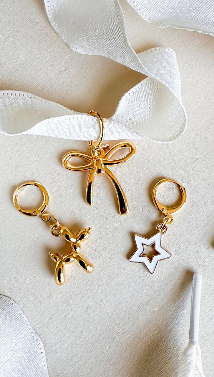 Gold-toned earrings and pendant with bow, balloon dog, and star charms.