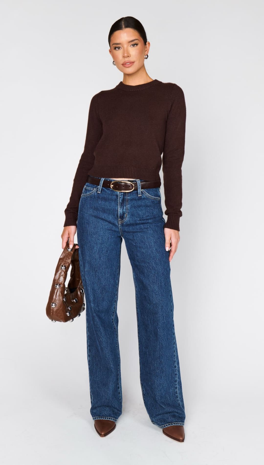 Women’s dark brown long-sleeve top with blue wide-leg jeans.