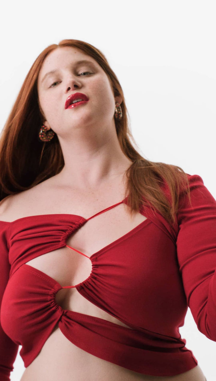 Red satin bow top with cutout design and long sleeves.