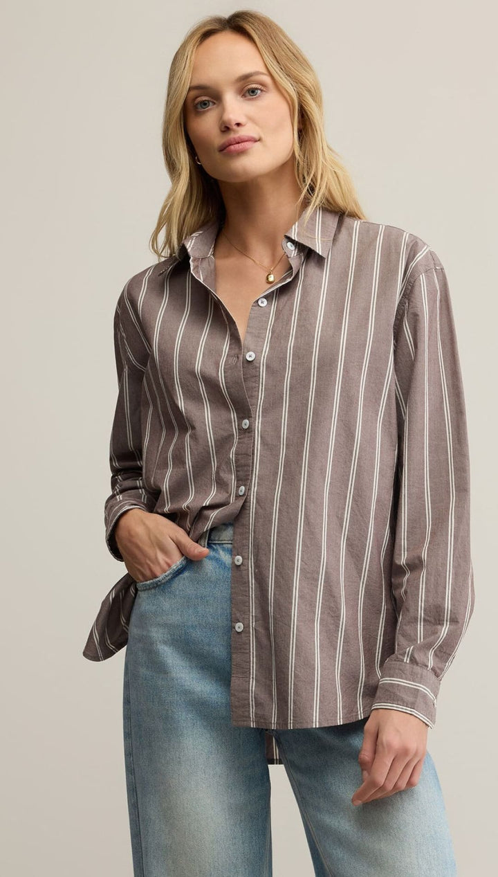 Women’s long-sleeved striped button-up shirt in a neutral tone paired with light wash denim jeans.