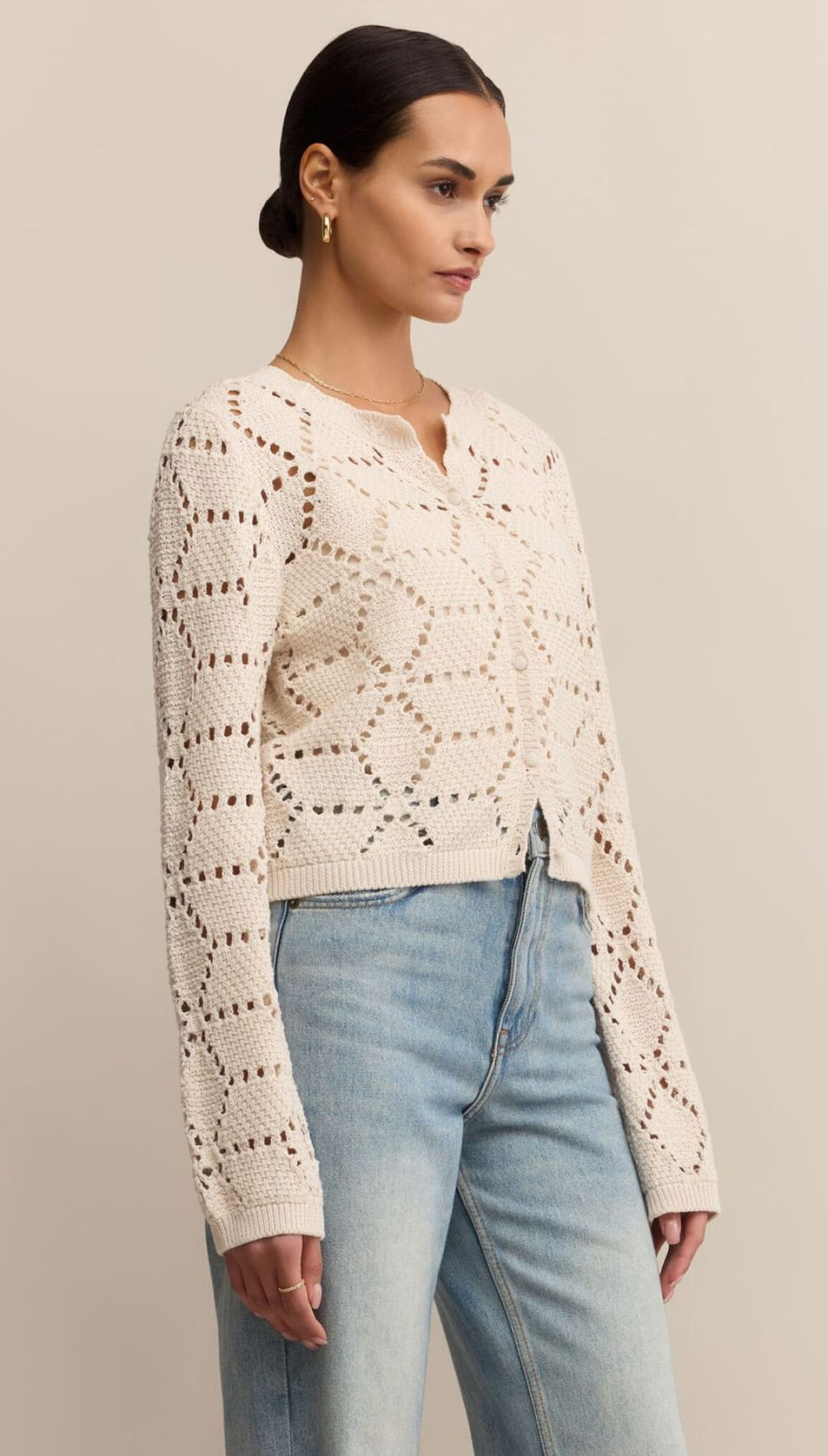 Cream-colored, open-knit cardigan with geometric patterns and a V-neckline.