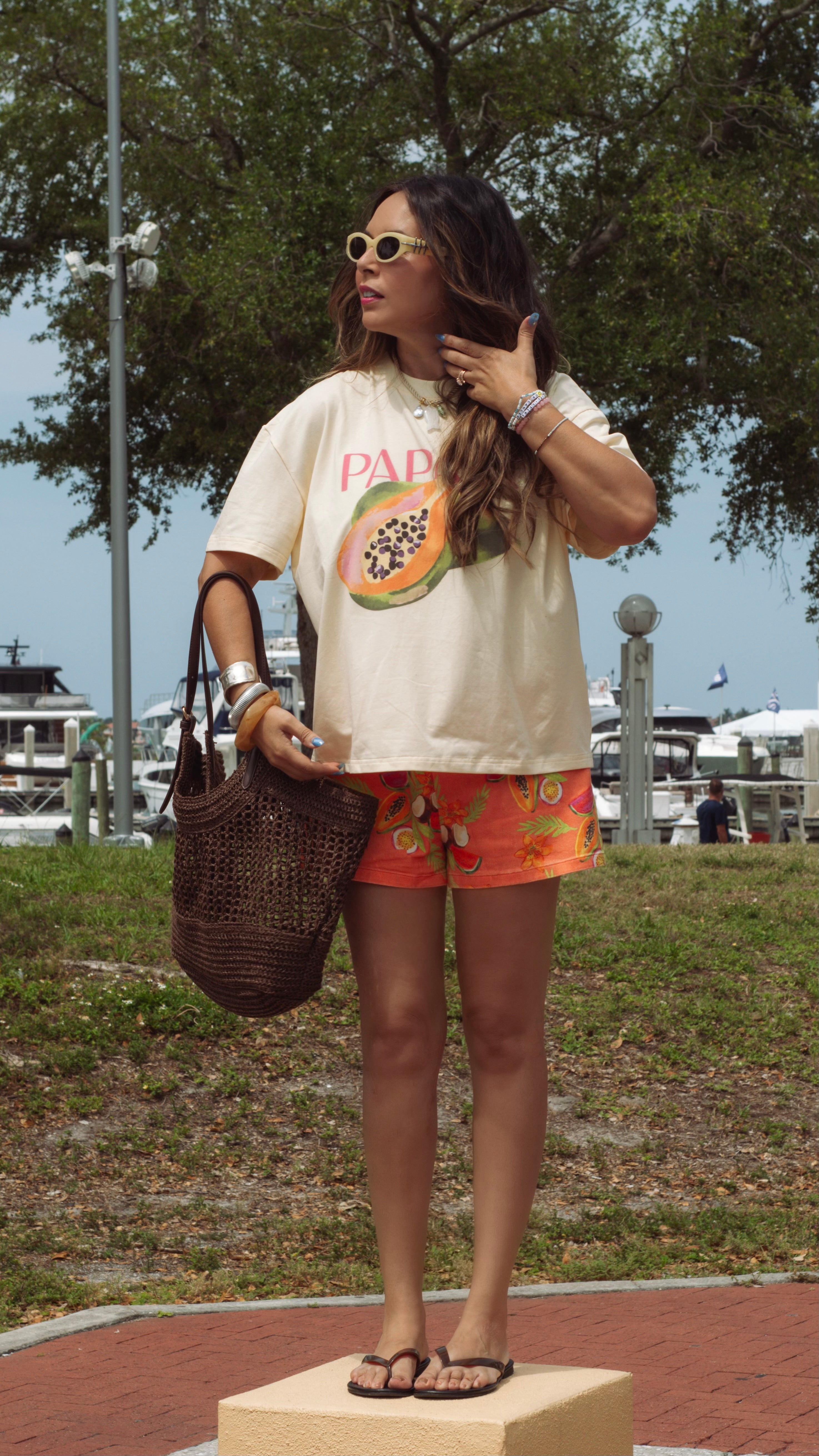 Woman wearing a graphic t-shirt and shorts with a beach setting in the background