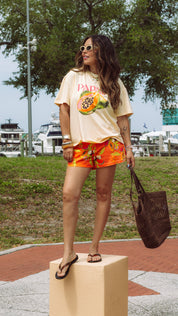 Woman in casual outfit with graphic t-shirt and shorts standing on a platform outdoors.