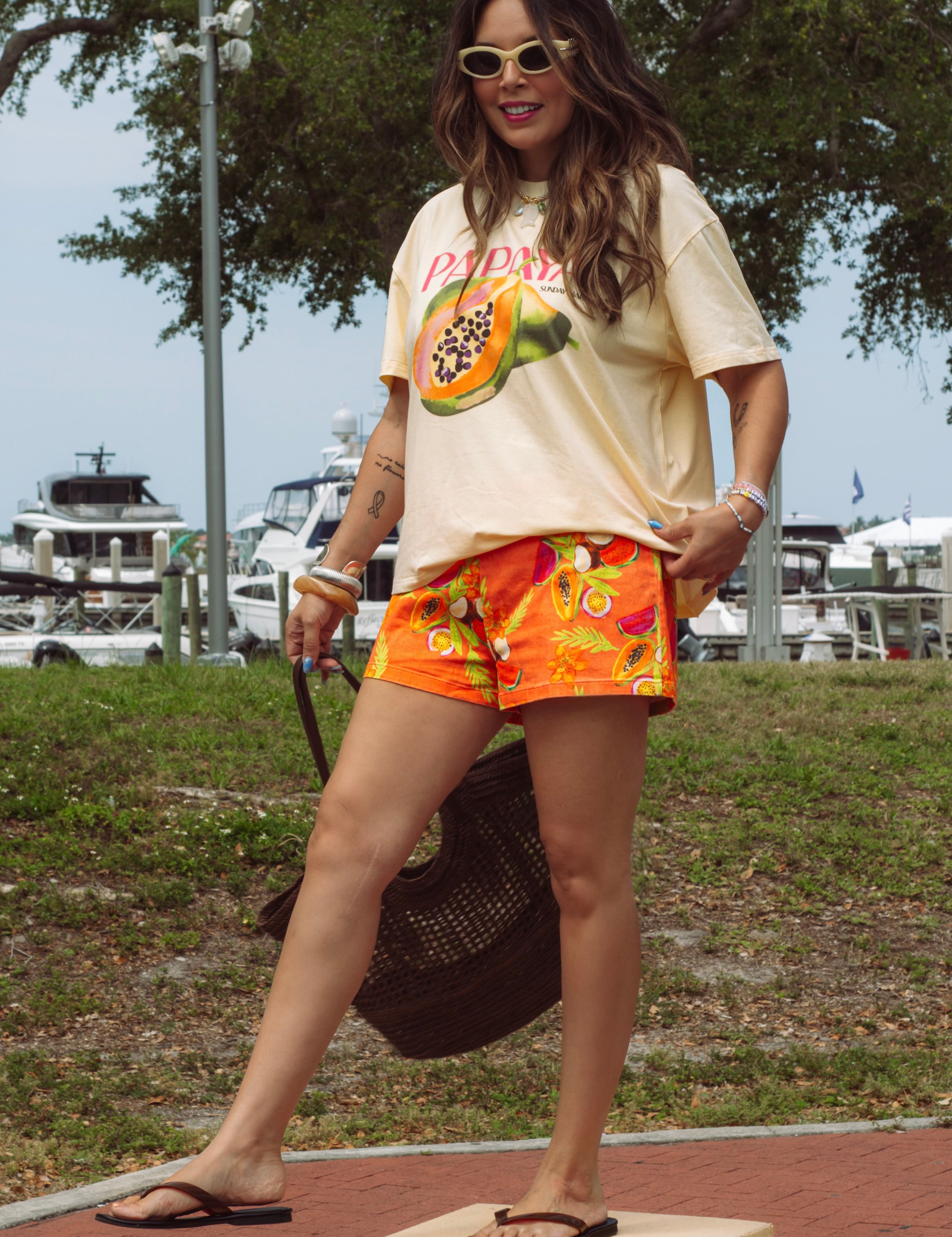 Woman wearing a graphic t-shirt and colorful shorts standing on a box outdoors.