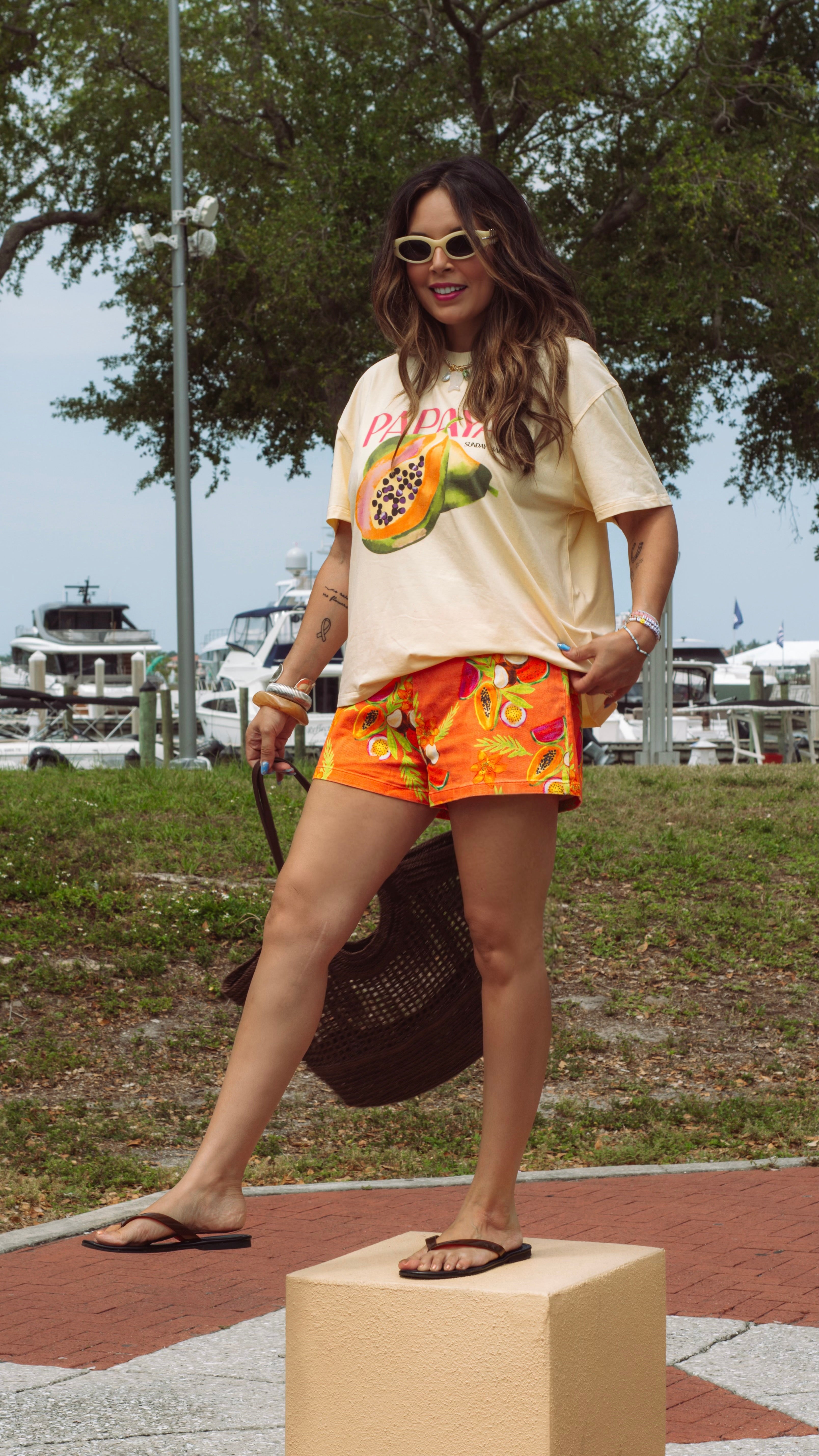 Woman wearing a graphic t-shirt and colorful shorts standing on a box outdoors.