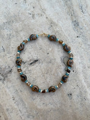 Necklace with brown and blue beads on a textured stone surface