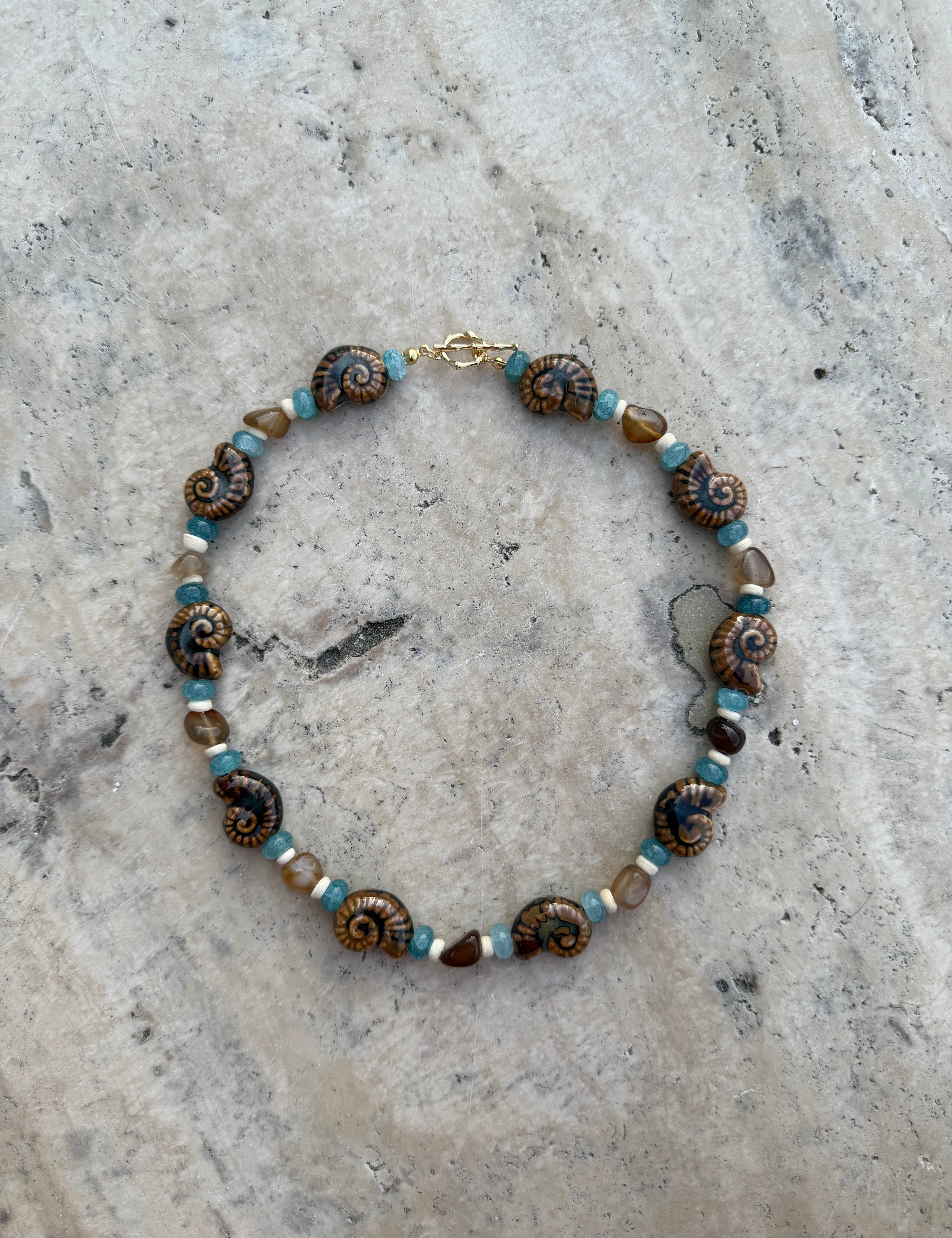 Necklace with brown and blue beads on a textured stone surface
