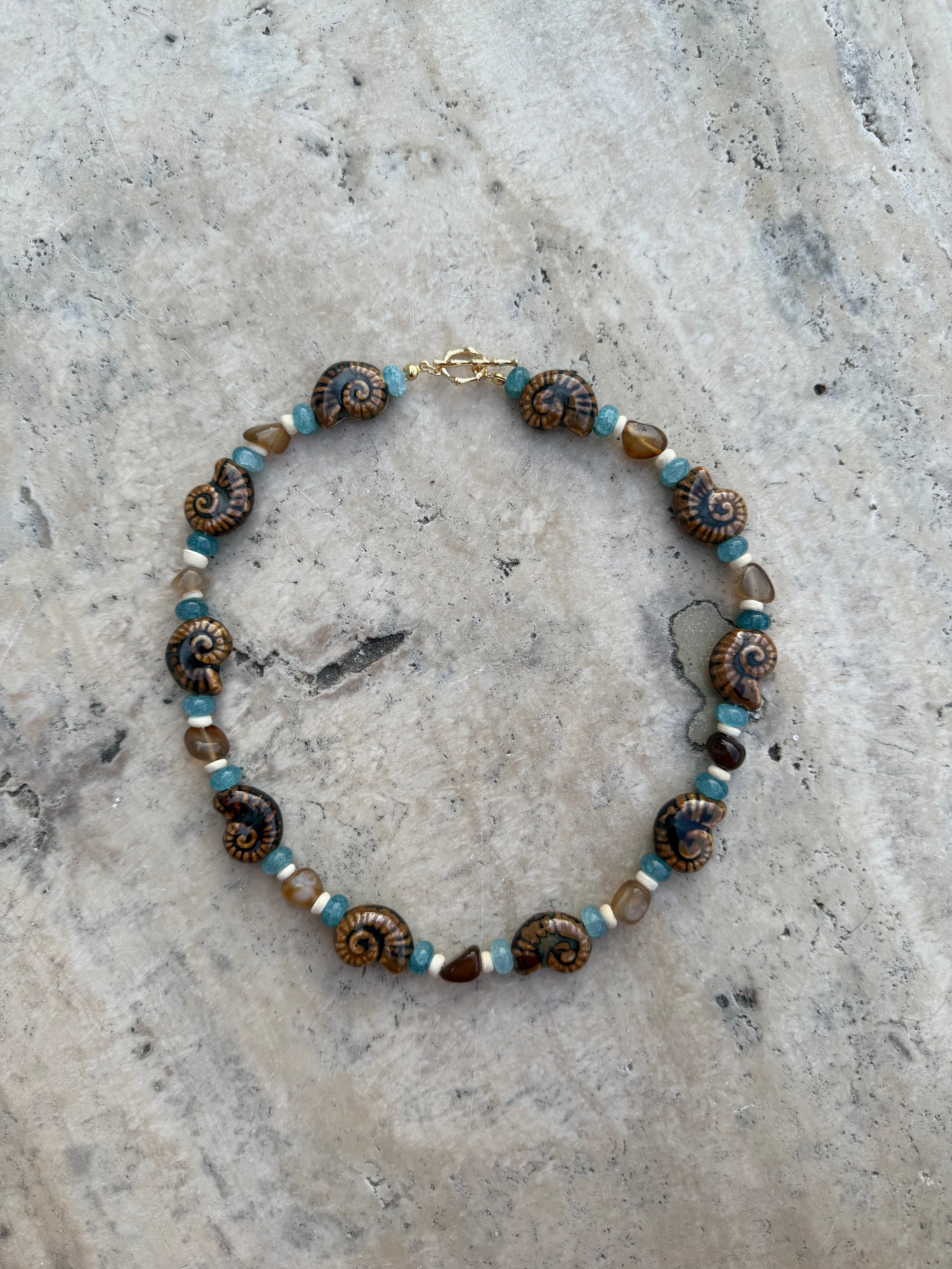 Necklace with brown and blue beads on a textured stone surface