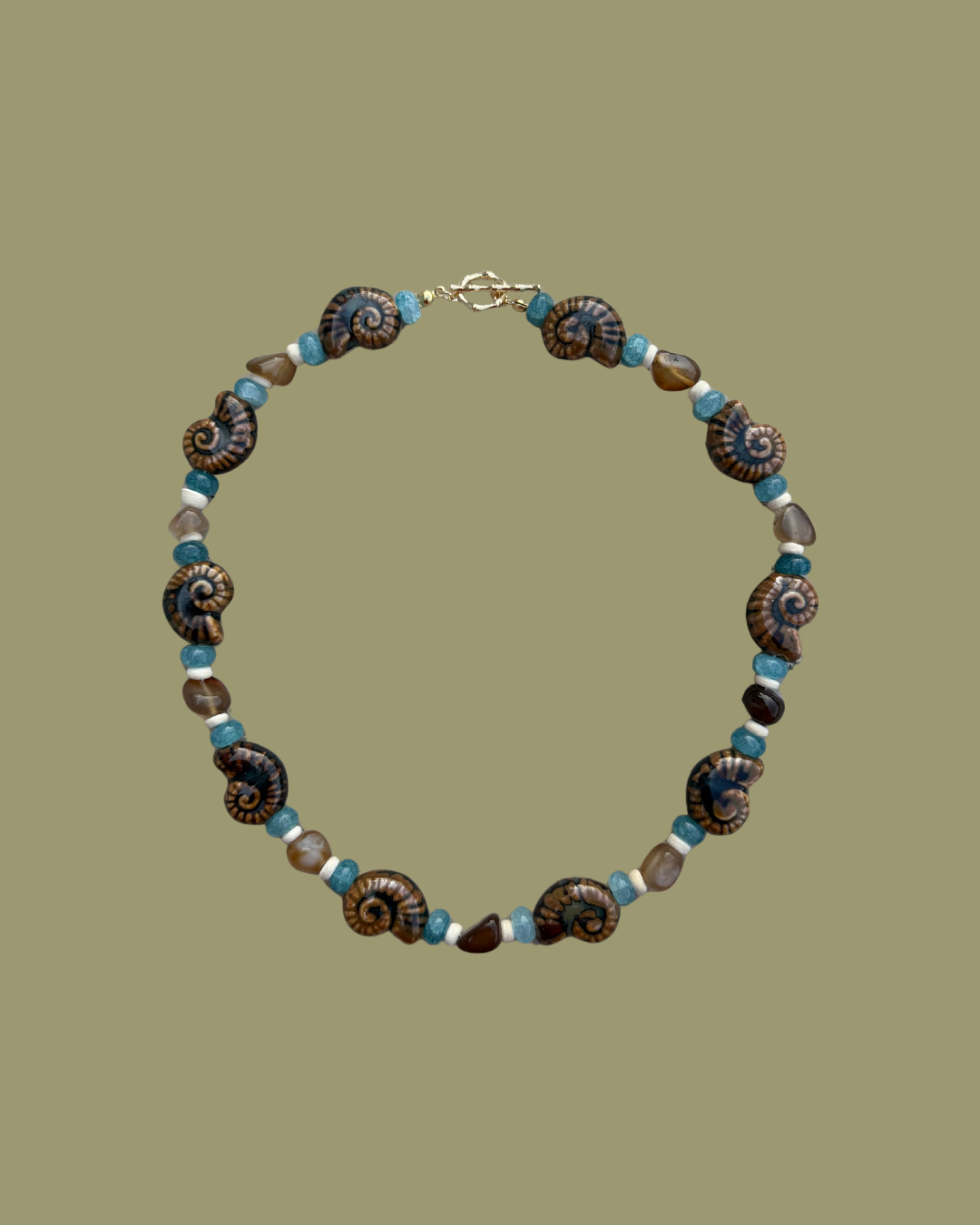 Necklace with ammonite fossils and blue beads on a green background