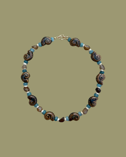 Necklace with ammonite fossils and blue beads on a green background