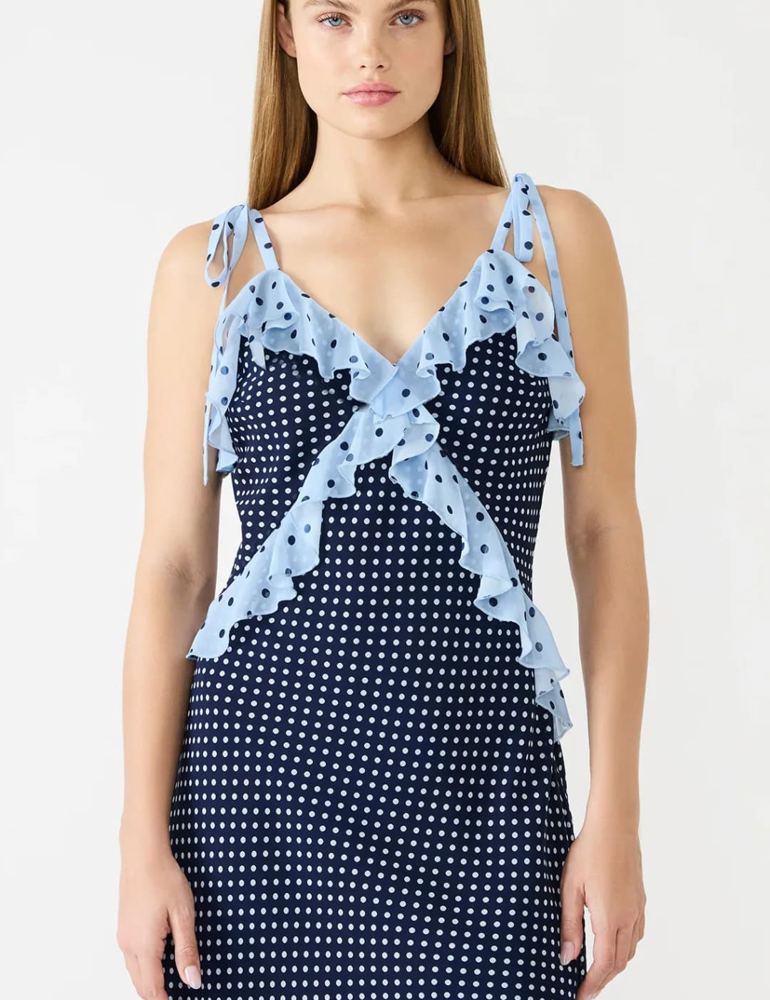 A navy blue polka dot dress with light blue ruffled straps and a matching ruffle detail at the neckline.