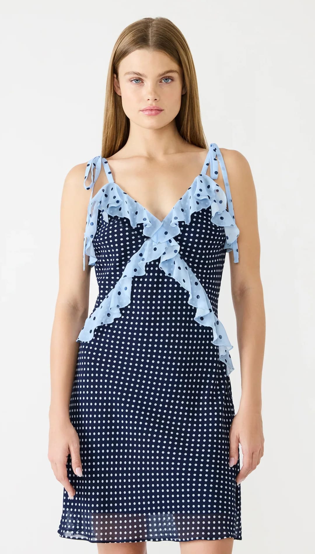 A navy blue polka dot dress with light blue ruffled straps and a matching ruffle detail at the neckline.
