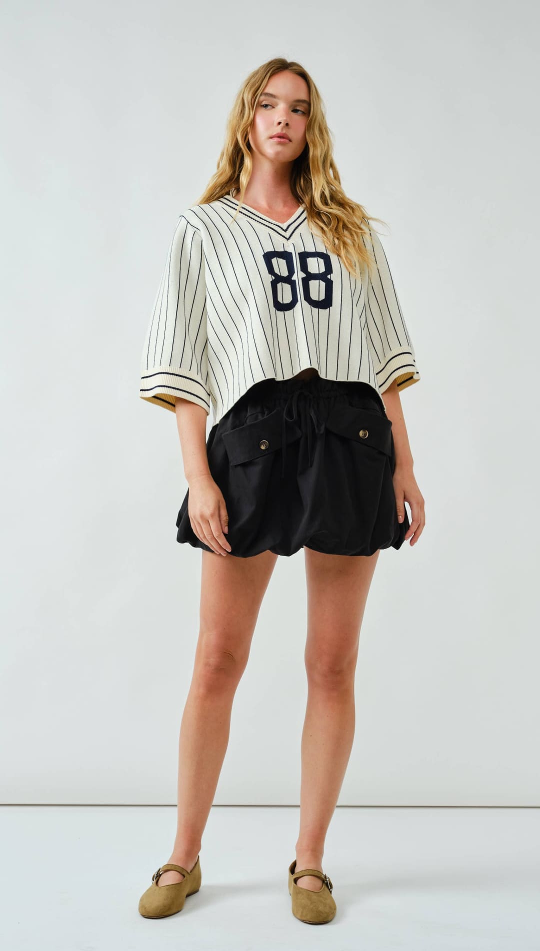 88 pinstripe baseball jersey with black shorts and tan loafers.