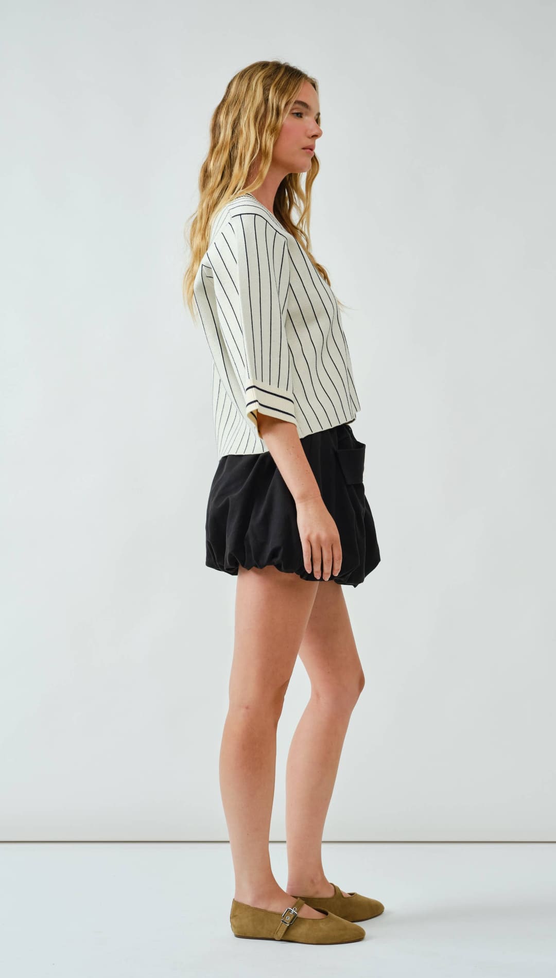 Black ruffled mini skirt with olive green suede loafers and striped blouse.