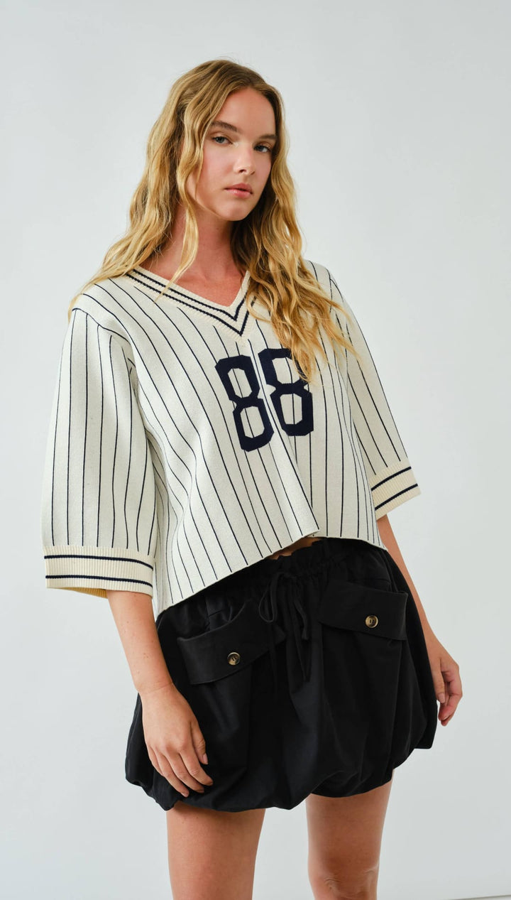 Striped baseball jersey with the number 86 in navy blue on a white background, made of cotton and polyester blend.