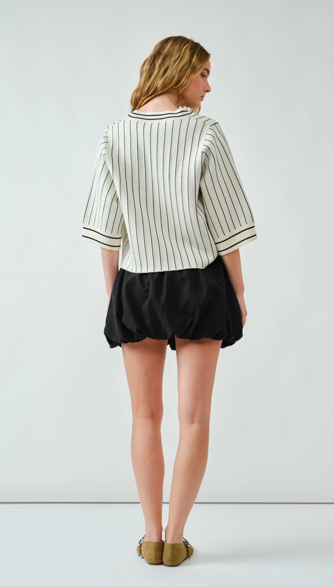 Striped knit sweater with black shorts and mustard-colored moccasins.