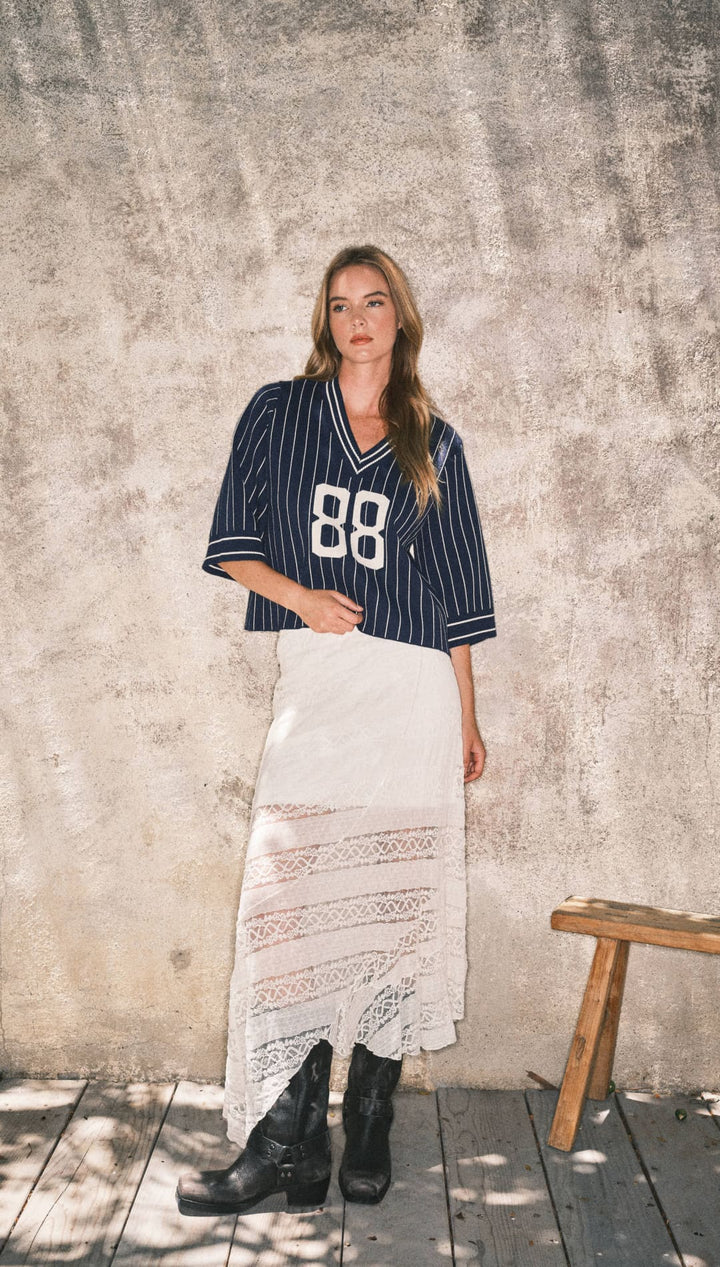 Striped navy blue and white baseball jersey with the number 88, black leather boots.