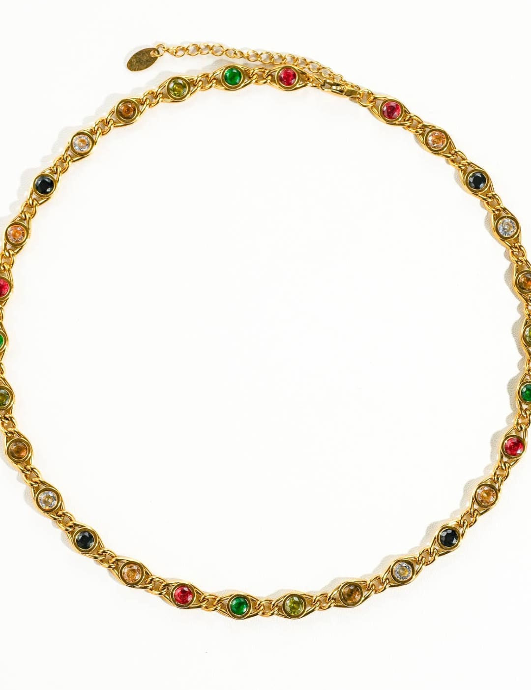 A gold-toned necklace featuring a chain with alternating colorful gemstones in red, green, and black set within ornate metal bezels.