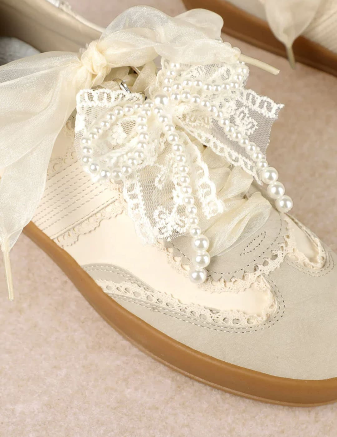 White lace and pearl embellished sneaker with gum sole.