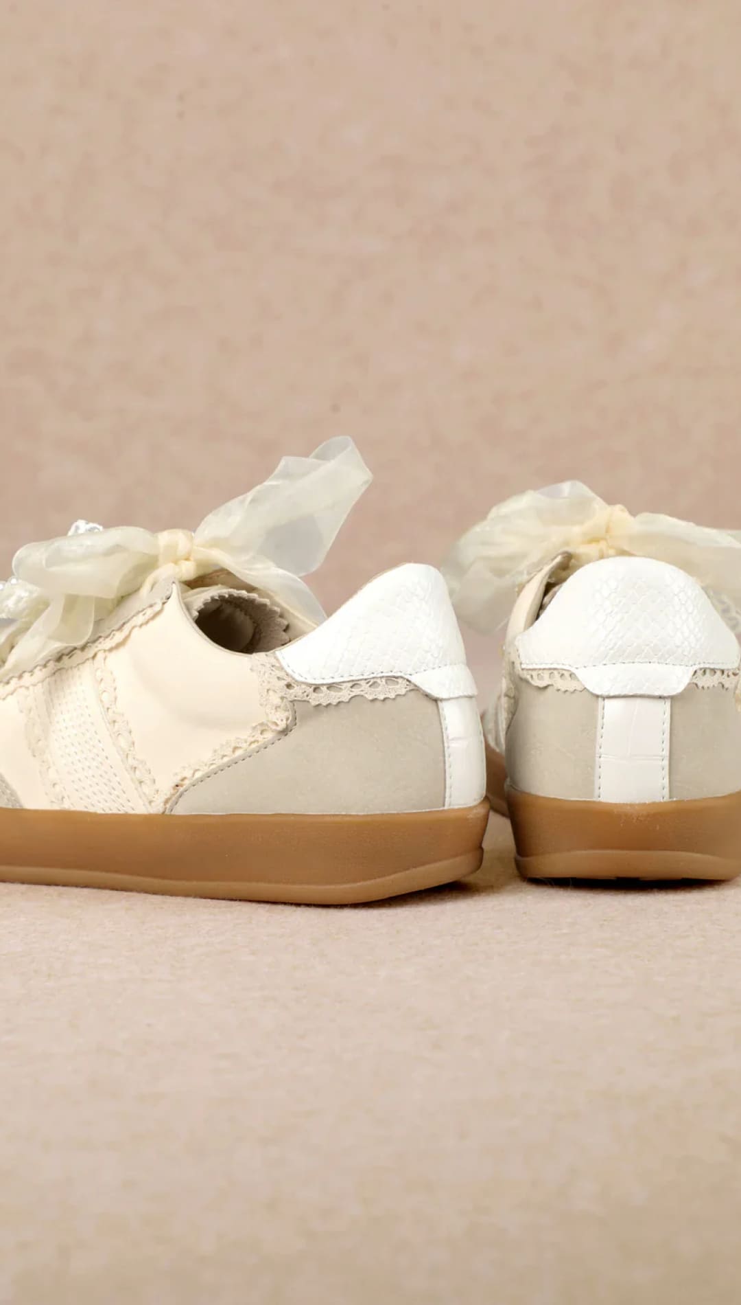 White lace-up sneakers with gold accents and bows, possibly by anthropologie.