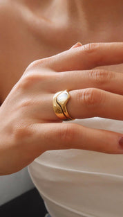 Gold ring with a smooth, wavy band and an embedded white opal stone.