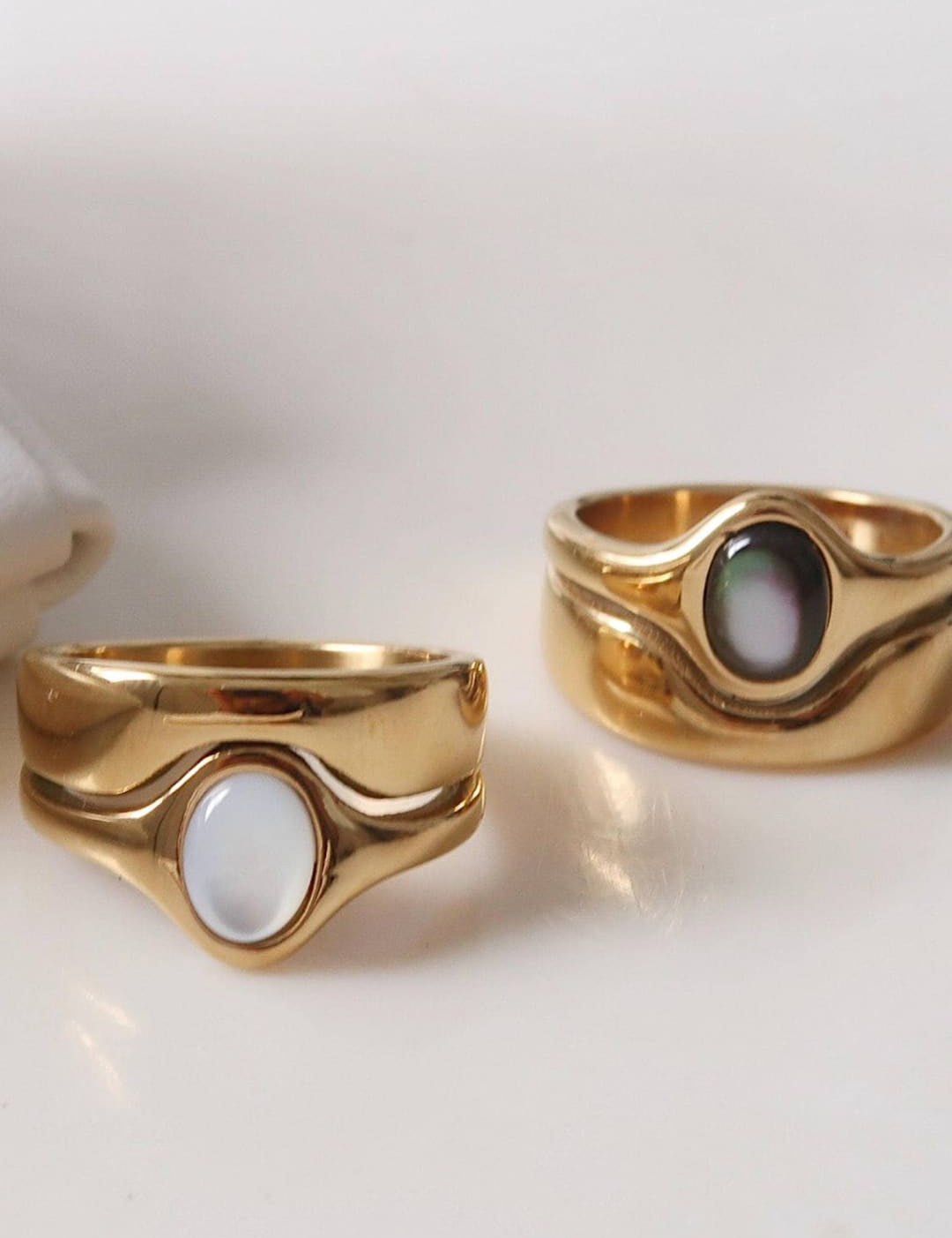 Gold-toned rings with smooth, wavy bands and oval-shaped mother-of-pearl inlays.