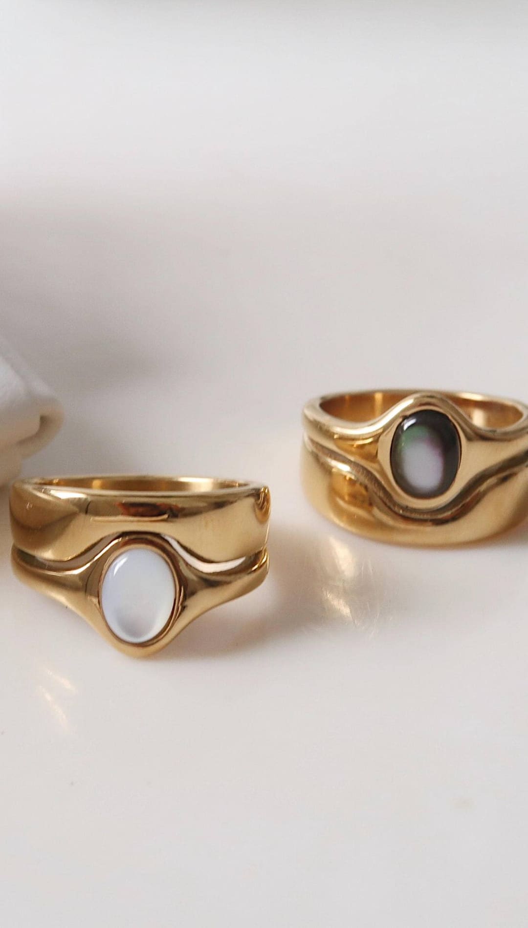 Gold-toned rings with smooth, wavy bands and oval-shaped mother-of-pearl inlays.