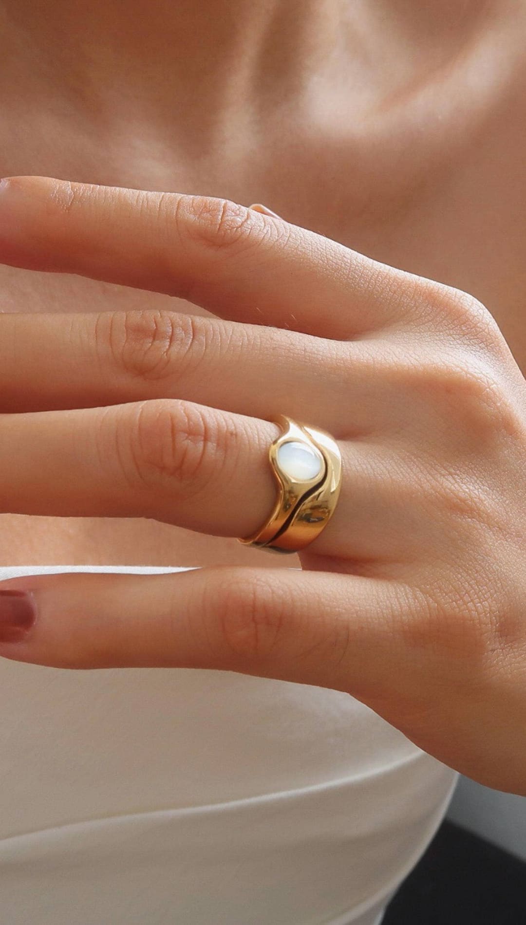 A gold-toned ring with a smooth, curved band and an oval-shaped white opal centerpiece.