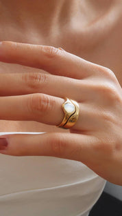 A gold-toned ring with a smooth, curved band and an oval-shaped white opal centerpiece.