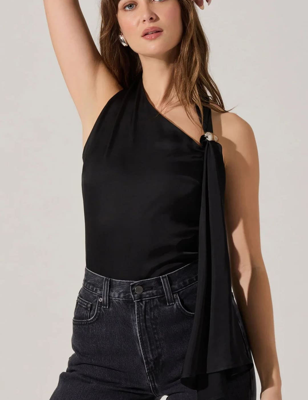 Women’s black one-shoulder top with a draped detail and a decorative ring.