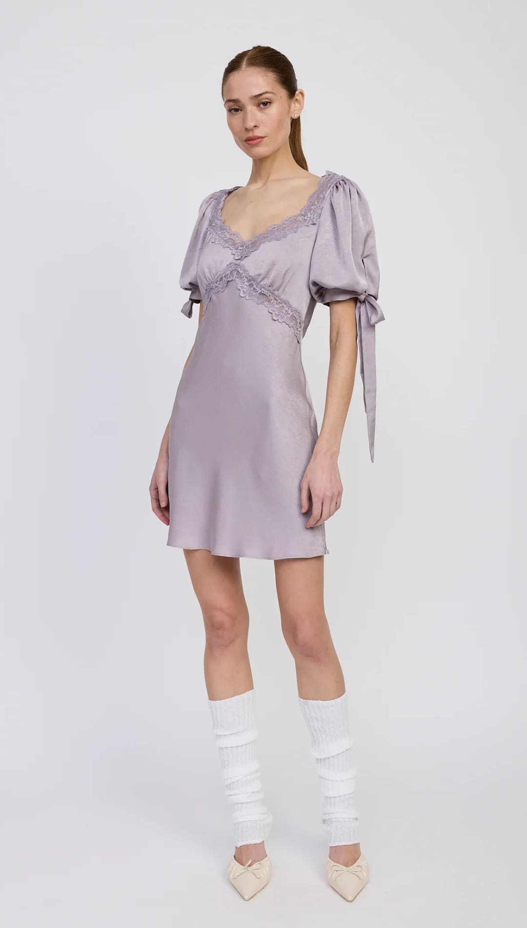 A lavender-colored satin mini dress with puff sleeves, lace trim, and tie details.