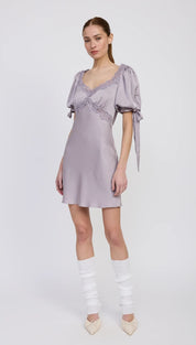A lavender-colored satin mini dress with puff sleeves, lace trim, and tie details.