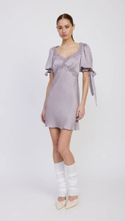 Lavender satin mini dress with puff sleeves, lace trim, and ribbon ties.